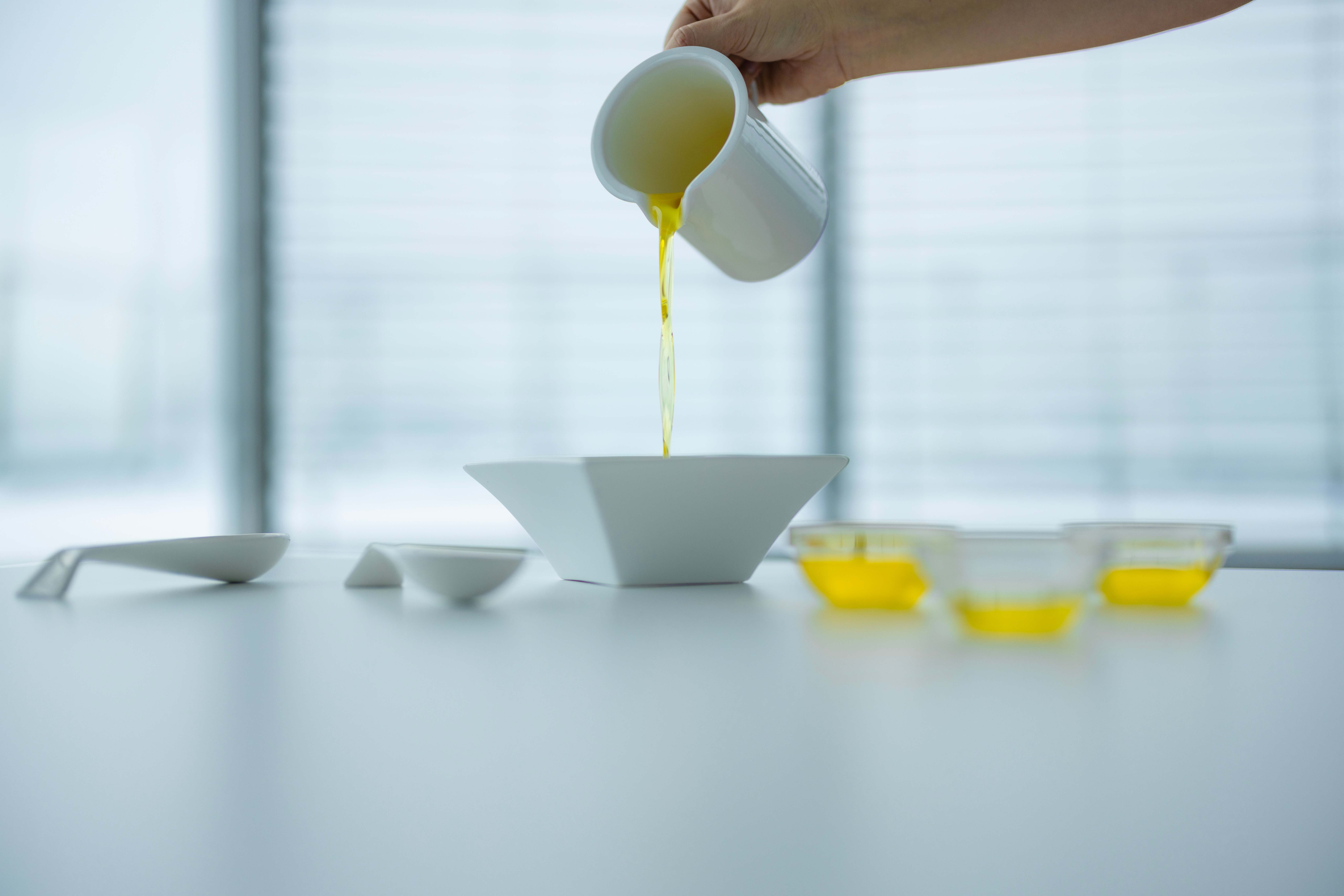 Clear, yellow chicken oil poured into a bowl from a white mug.