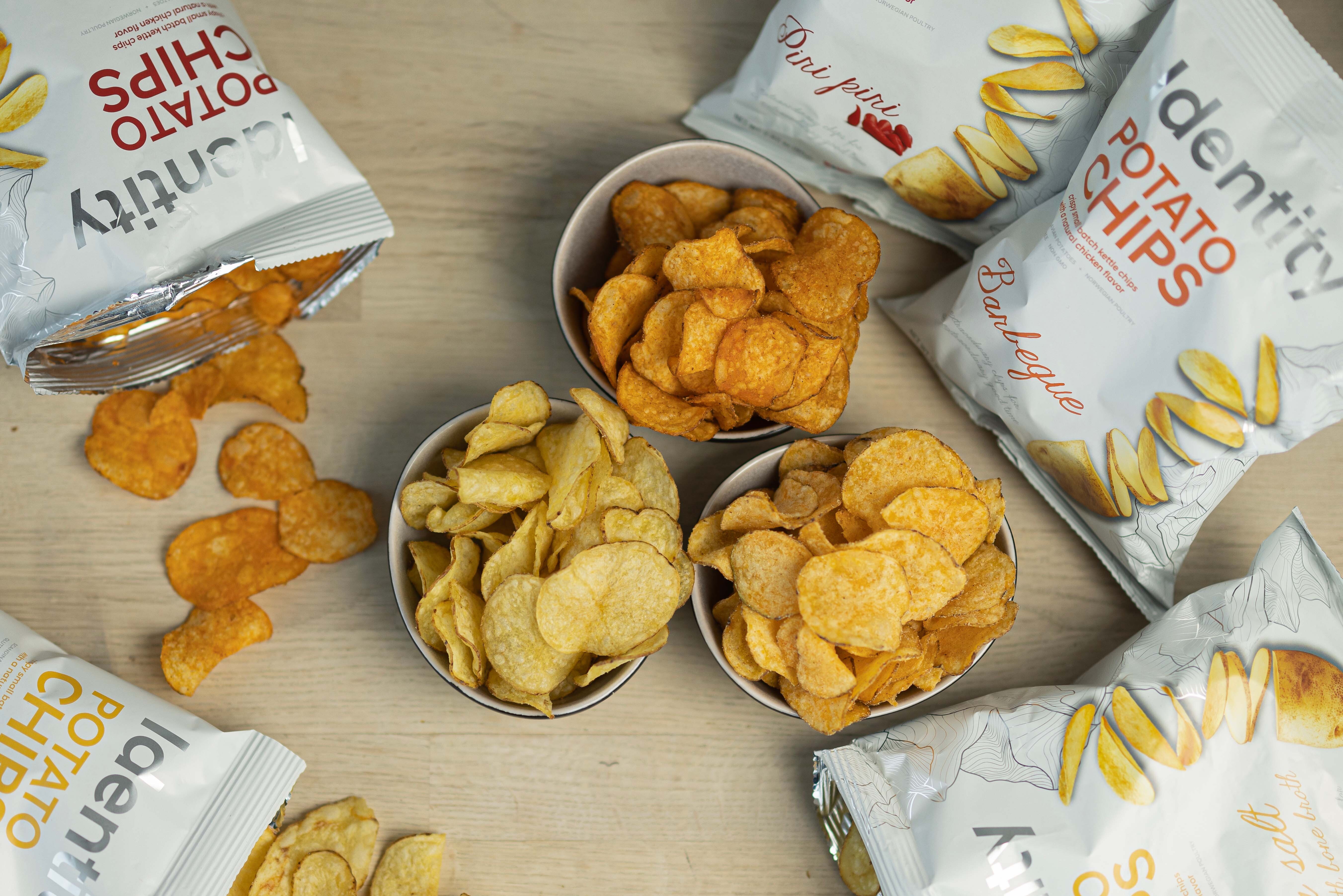 Three bowls filled with potato crisps in different flavors seen from above.